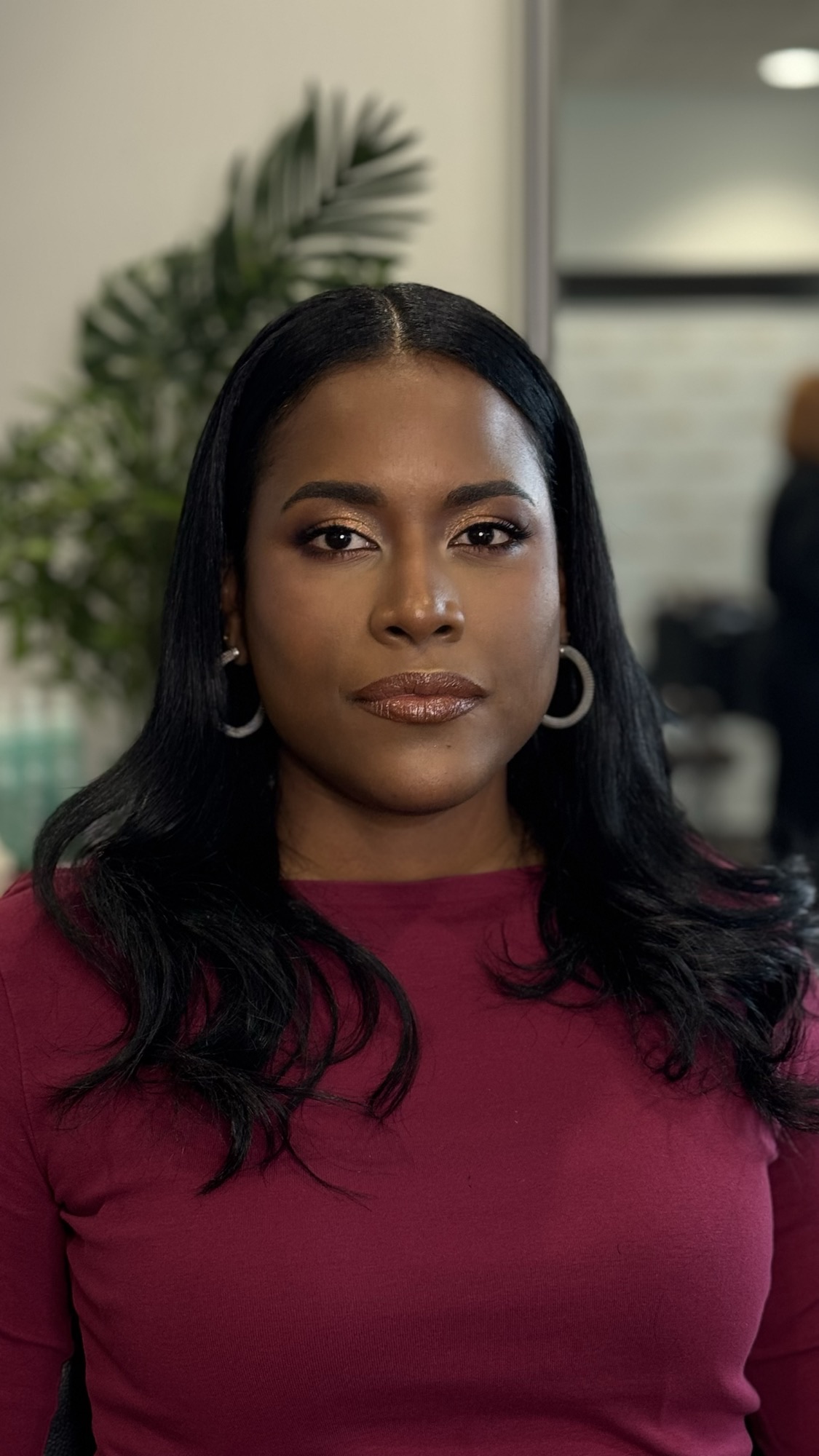 Close-up headshot of Yazuri Guido in a burgundy top with hoop earrings and gold-toned makeup